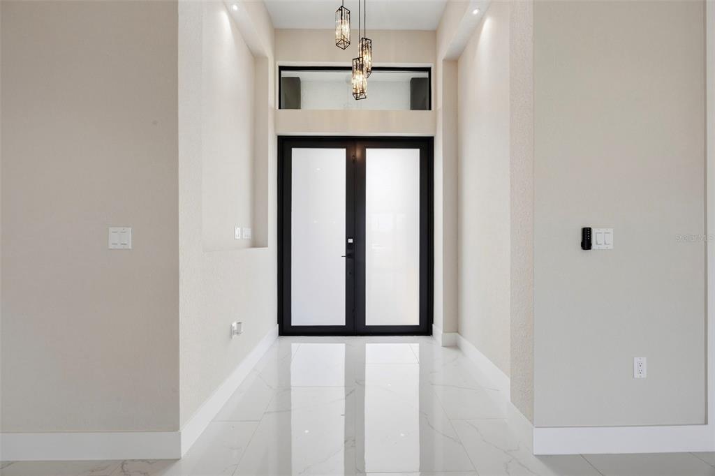 A bright entryway features white marble floors, a double glass door, and modern pendant lighting — 90 BRIG CIRCLE S, PLACIDA, FL
