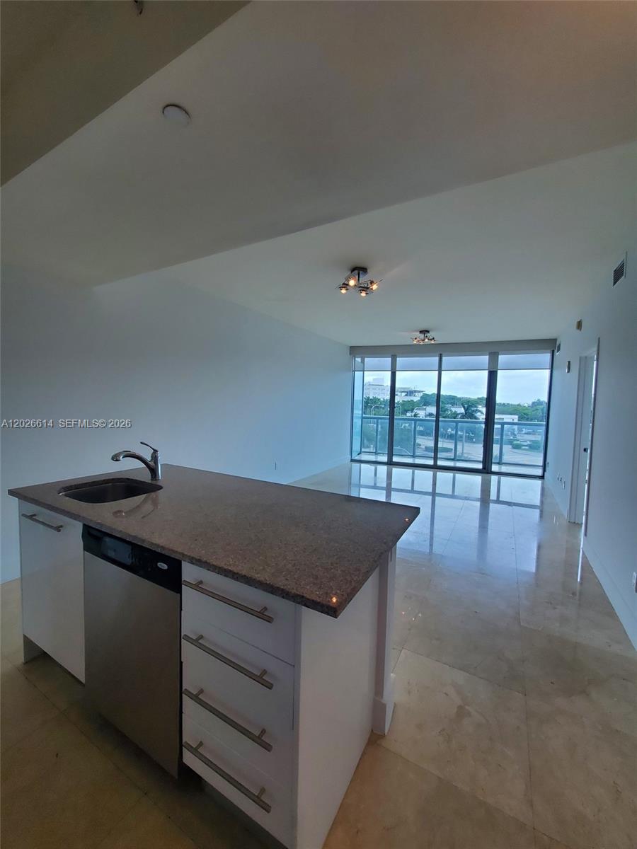 A kitchen island with a sink and dishwasher faces an open living area with floor-to-ceiling windows — 888 Biscayne Blvd # 311, Miami FL 33132, MIAMI, FL