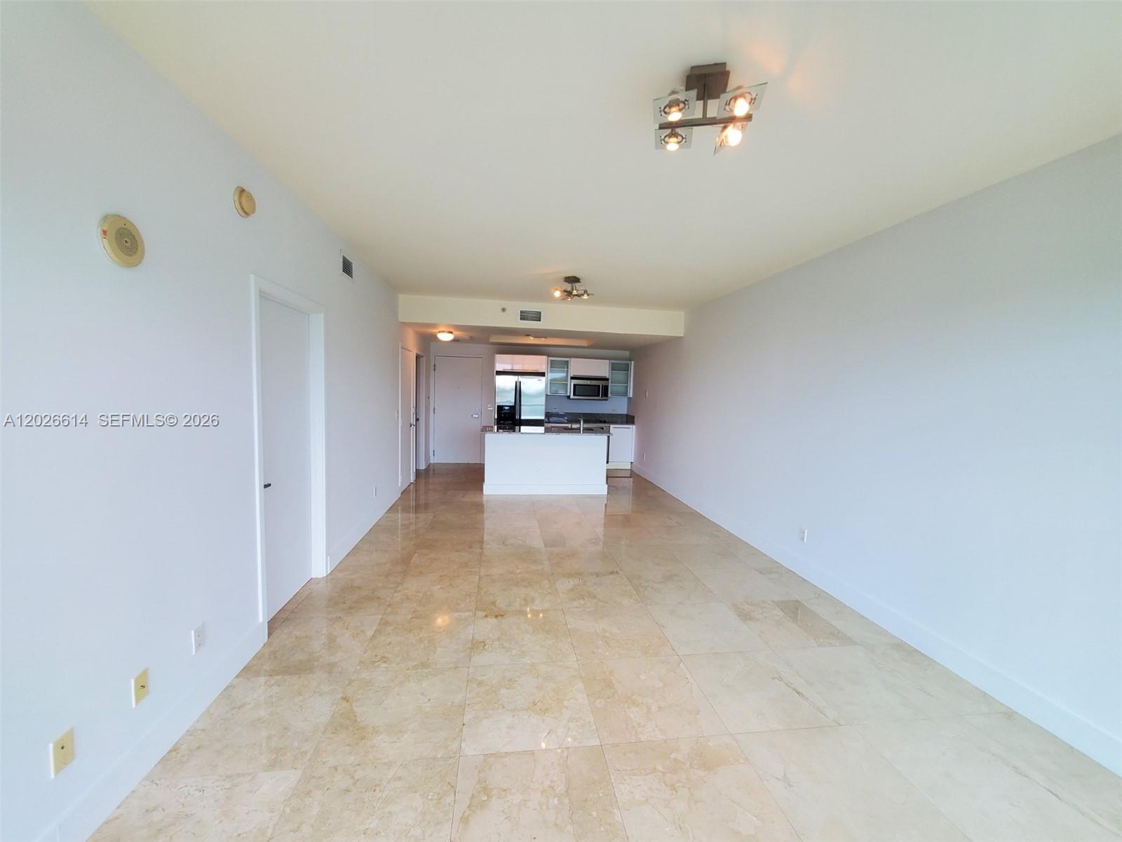 An open-concept living area features light-colored tile flooring, white walls, and a kitchen island — 888 Biscayne Blvd # 311, Miami FL 33132, MIAMI, FL