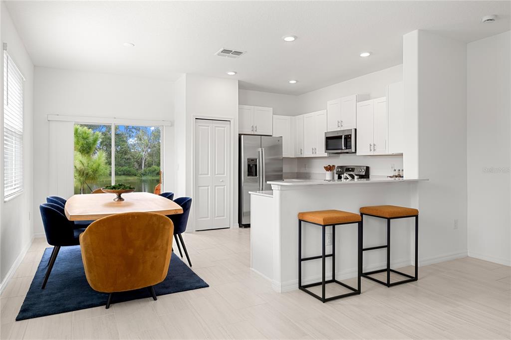 A kitchen and dining area with white cabinets, stainless steel appliances, and a view of water — 5095 CAPRI HARBOR DRIVE, WIMAUMA, FL