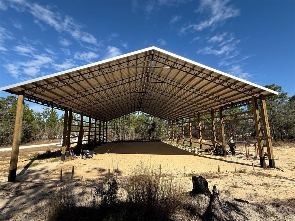 An open-sided pole barn structure features wooden support posts and a metal roof — 16386 KAKAWI ROAD, WEEKI WACHEE, FL