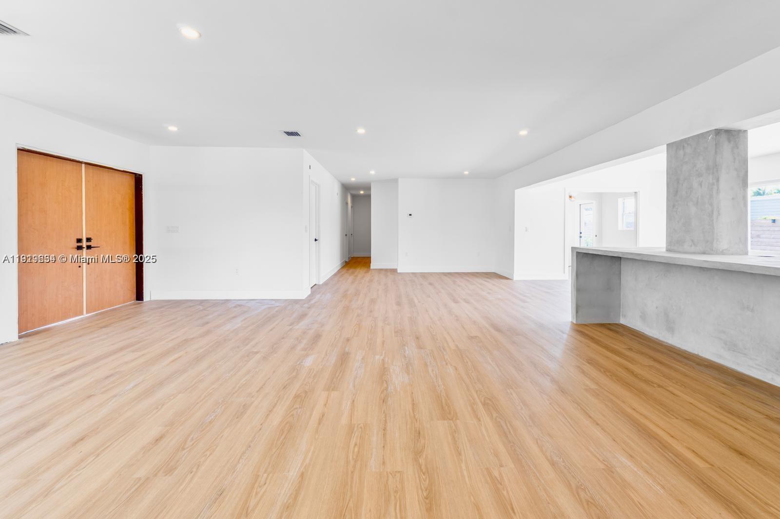 A bright, open-concept living area features light wood flooring, white walls, and a concrete island — 19661 NE 10th Pl, Miami FL 33179, MIAMI, FL
