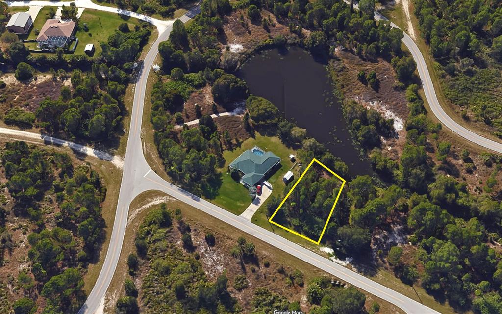 An aerial view shows a vacant, wooded lot outlined in yellow next to a house — 27539 MONTE CRISTO BOULEVARD, PUNTA GORDA, FL