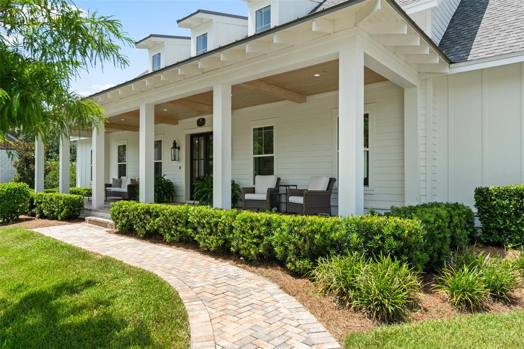 A brick walkway leads to a covered front porch of a white farmhouse-style home — 15217 FARM STAND COURT, WINTER GARDEN, FL