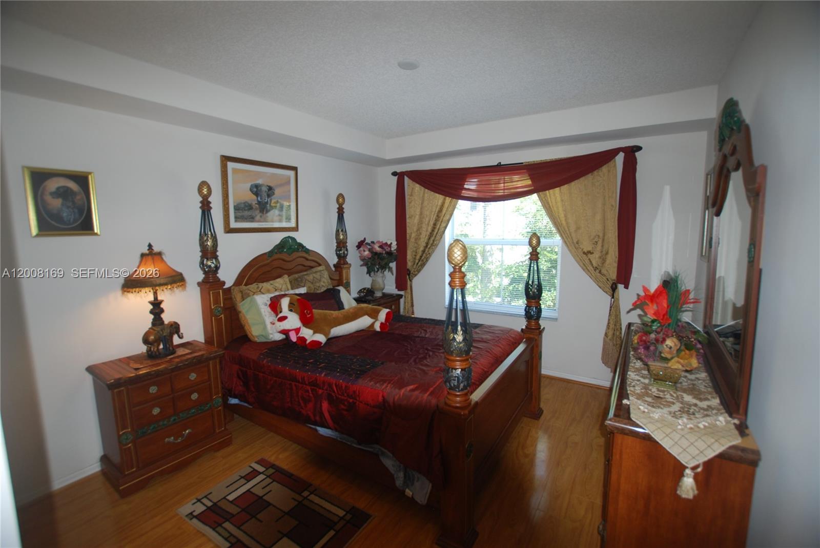 A bedroom features a wooden four-poster bed, matching nightstand, dresser with mirror, and hardwood floors — 1310 Tuscany Way # 1310, Boynton Beach FL 33435, BOYNTON BEACH, FL