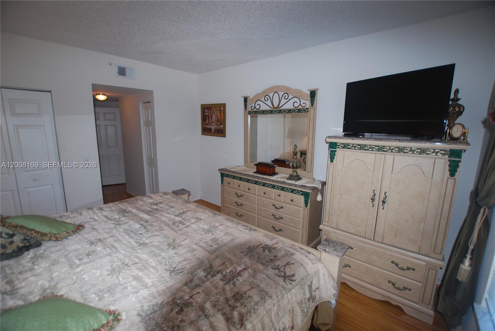 A bedroom features a bed, a dresser with a mirror, and an armoire with a television — 1310 Tuscany Way # 1310, Boynton Beach FL 33435, BOYNTON BEACH, FL