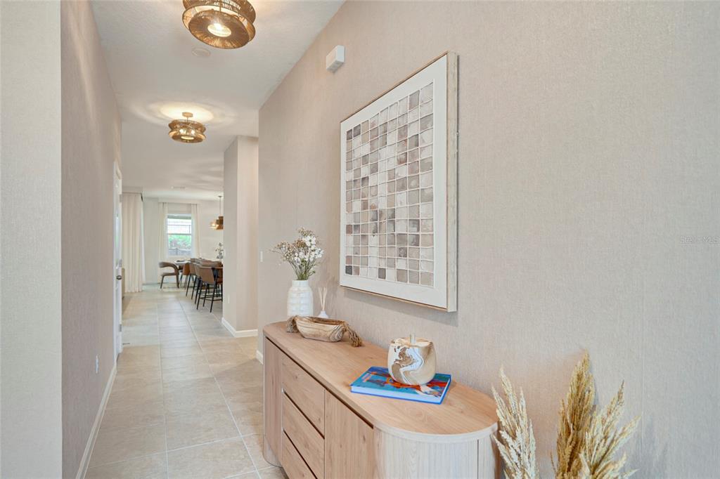 A hallway features a light wood console table, wall art, and tile flooring — 9194 SEASCAPE COVE, KISSIMMEE, FL