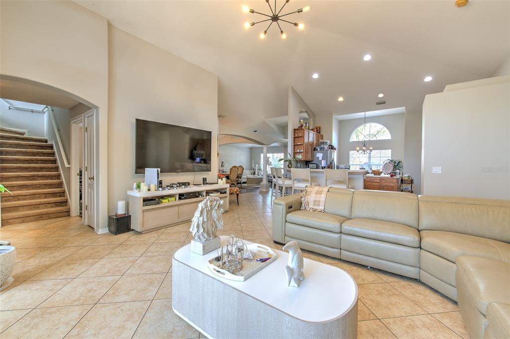 A living room with tile floors, a large sectional sofa, and a wall-mounted television — 4639 POINTE O WOODS DRIVE, WESLEY CHAPEL, FL