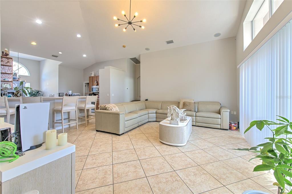 A living room with tile flooring, a beige sectional sofa, and a kitchen breakfast bar — 4639 POINTE O WOODS DRIVE, WESLEY CHAPEL, FL