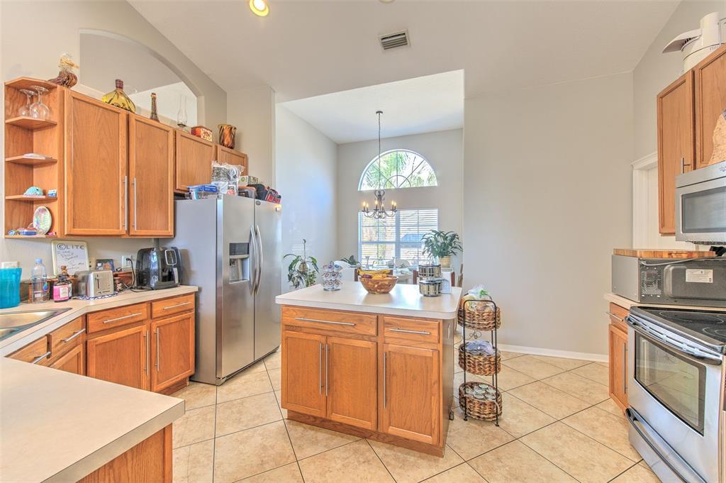 A kitchen with wood cabinets, stainless steel appliances, a center island, and tile flooring — 4639 POINTE O WOODS DRIVE, WESLEY CHAPEL, FL