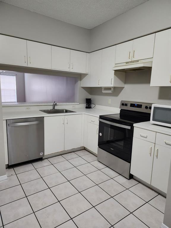 A kitchen features white cabinets, stainless steel appliances, and light-colored tile flooring — 51 Whitehead Circle # 51, Weston FL 33326, WESTON, FL