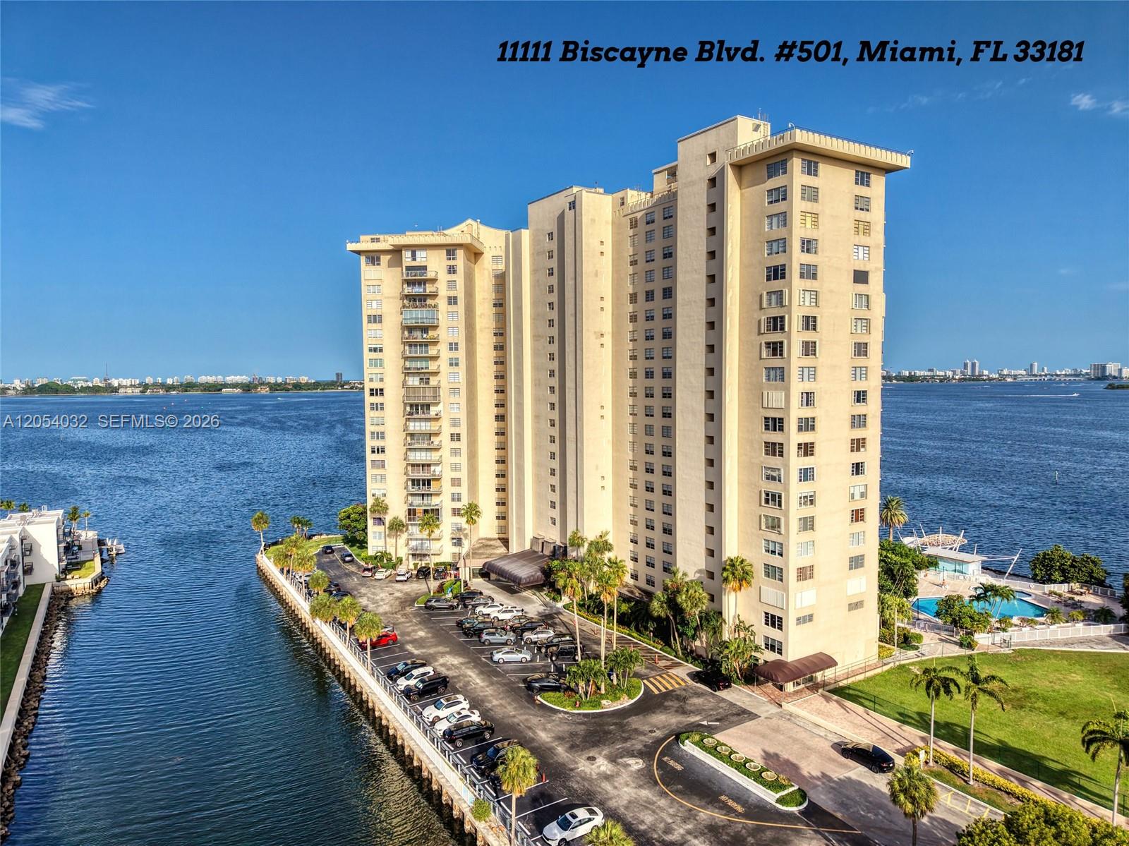 An aerial view shows a tall residential building surrounded by water and a parking lot — 11111 Biscayne Blvd # 5A, Miami FL 33181, MIAMI, FL