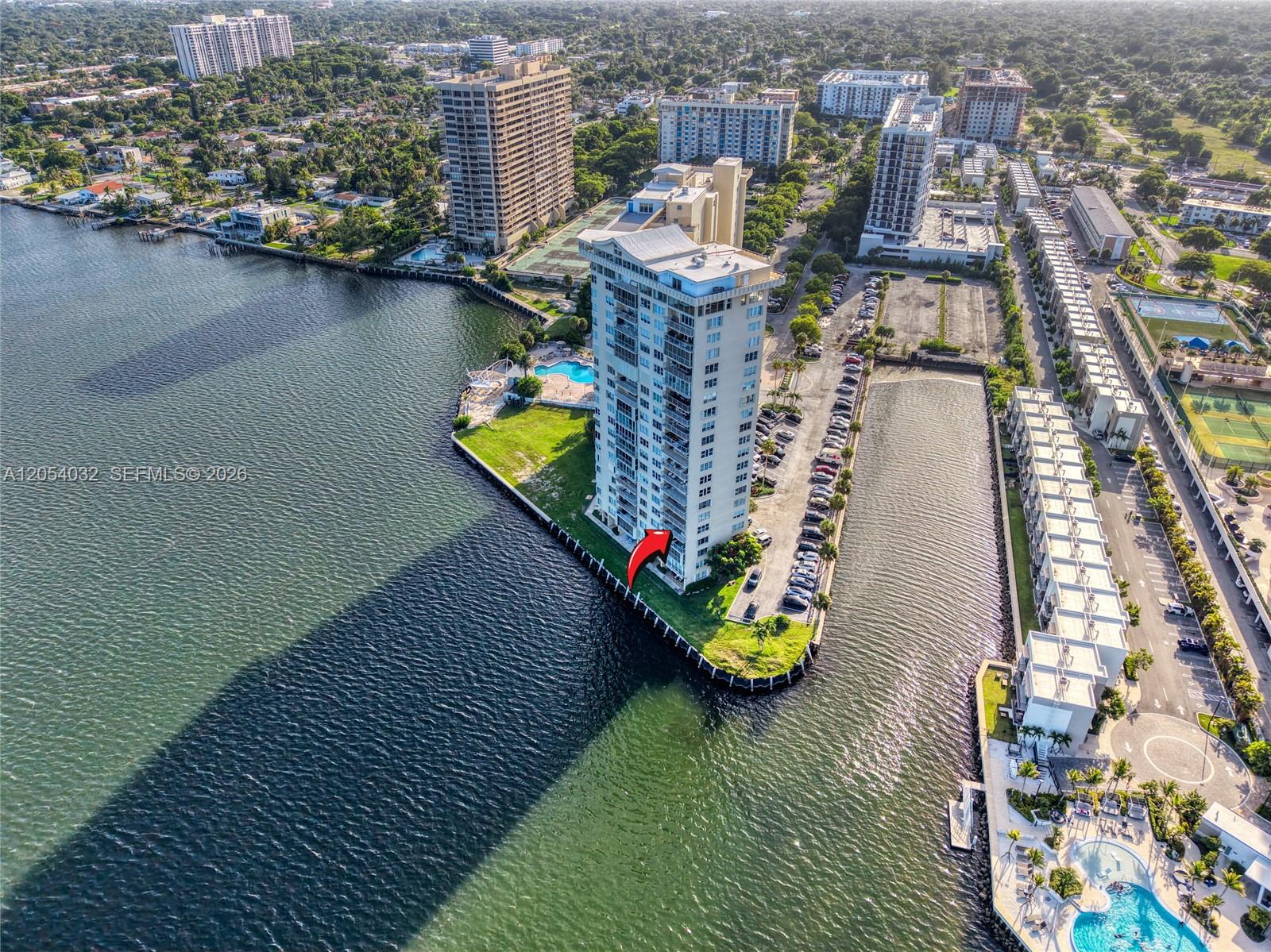 An aerial view shows a high-rise residential building situated on a waterfront point — 11111 Biscayne Blvd # 5A, Miami FL 33181, MIAMI, FL