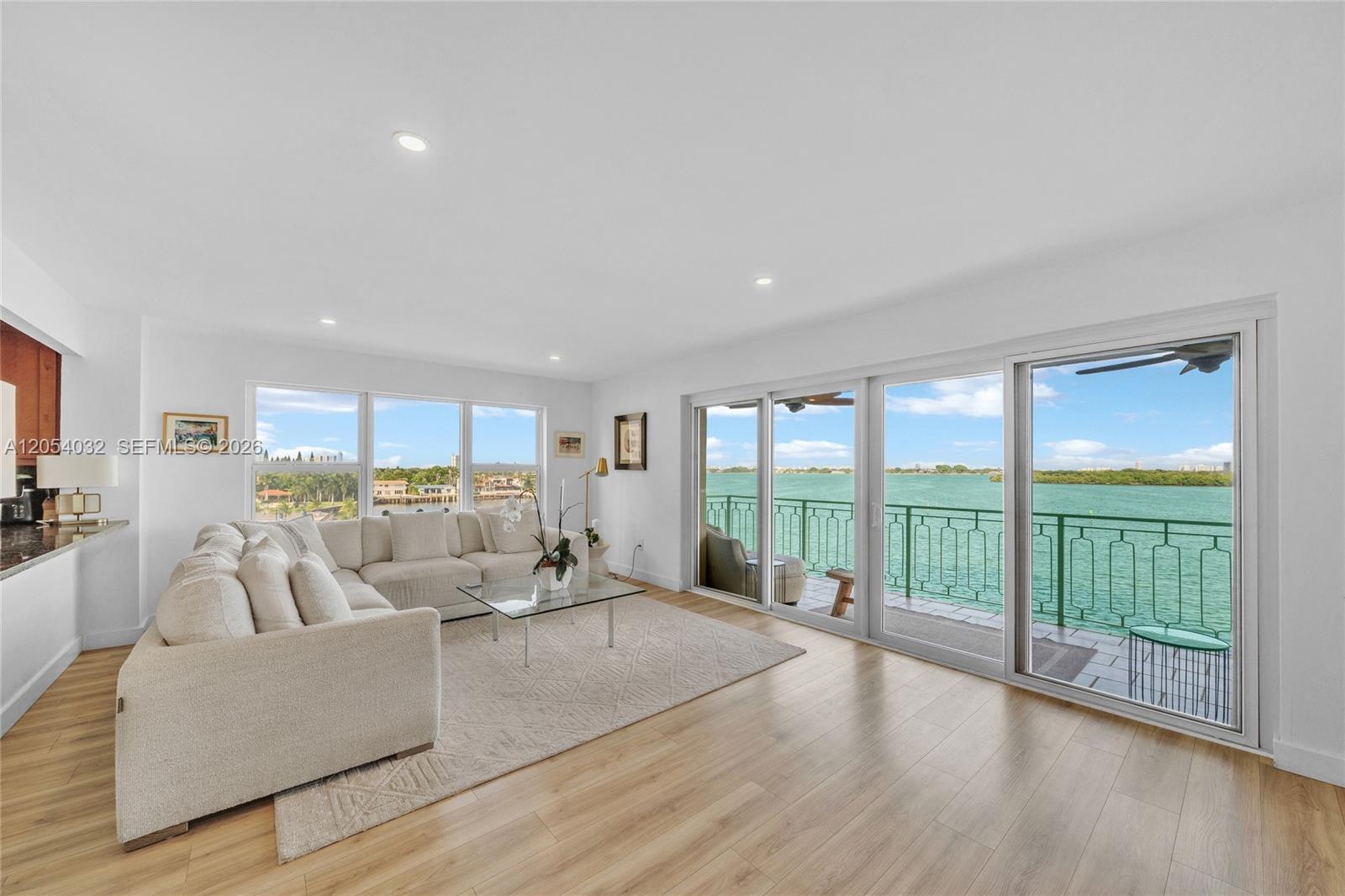 A living room features a large sectional sofa, light wood floors, and sliding glass balcony doors — 11111 Biscayne Blvd # 5A, Miami FL 33181, MIAMI, FL