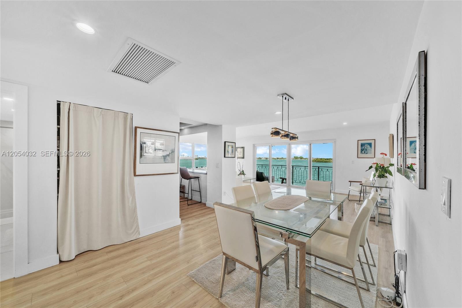 A dining area with a glass table and chairs overlooks a balcony with water views — 11111 Biscayne Blvd # 5A, Miami FL 33181, MIAMI, FL