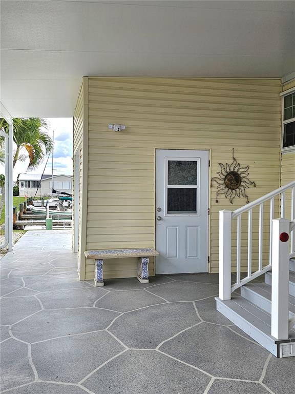 A covered patio with patterned concrete flooring, a small bench, and a white door — 29 BRINK AVENUE, PUNTA GORDA, FL