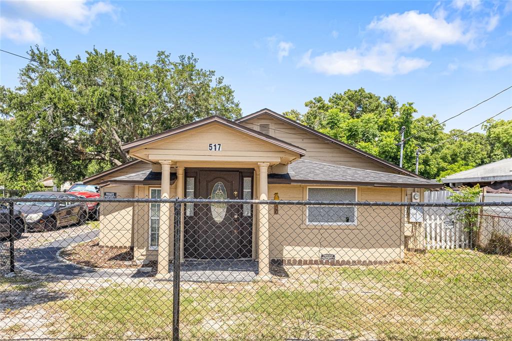 A tan, single-story house with a front porch and a chain-link fence in the yard — 517 OAK STREET, AUBURNDALE, FL
