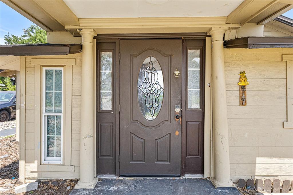 A brown front door with an oval glass insert is flanked by two columns — 517 OAK STREET, AUBURNDALE, FL