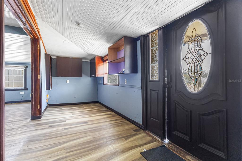 An entryway with light wood-look flooring, blue walls, dark cabinets, and a black front door — 517 OAK STREET, AUBURNDALE, FL