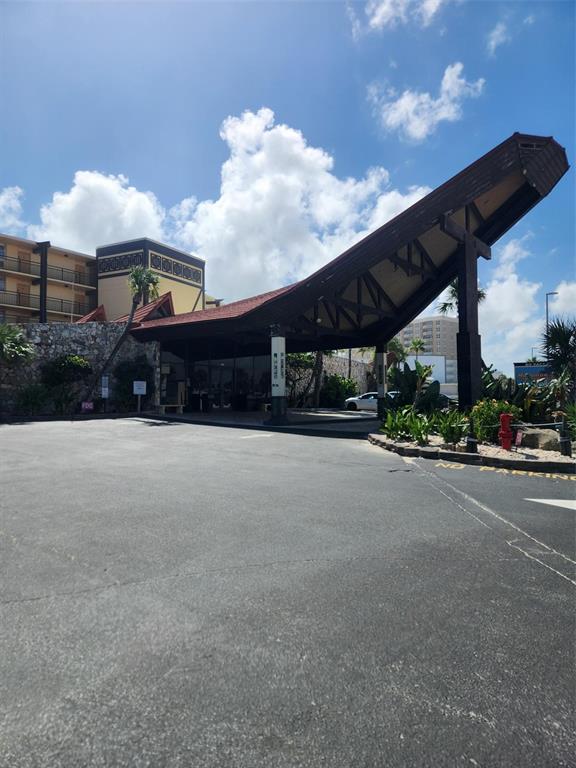 An exterior view of a hotel entrance with a large, angled roof and stone wall — 2301 S ATLANTIC AVENUE UNIT 520, DAYTONA BEACH, FL