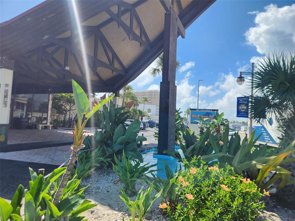 A view of a hotel entrance with a large wooden roof, landscaping, and a fountain — 2301 S ATLANTIC AVENUE UNIT 520, DAYTONA BEACH, FL