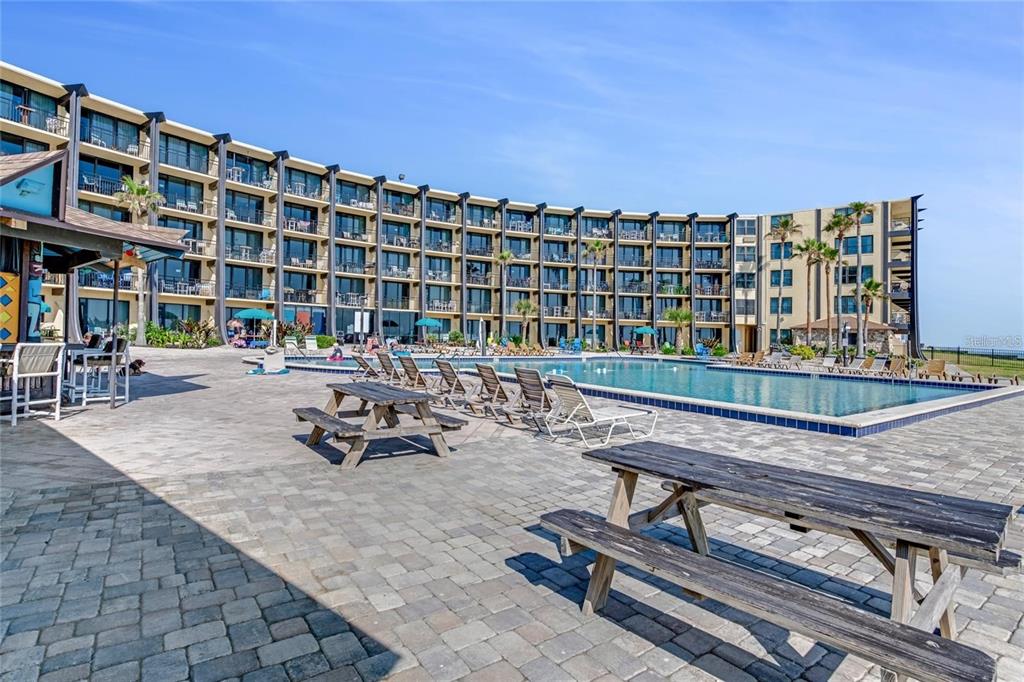 A multi-story hotel building overlooks a swimming pool with lounge chairs and picnic tables — 2301 S ATLANTIC AVENUE UNIT 520, DAYTONA BEACH, FL