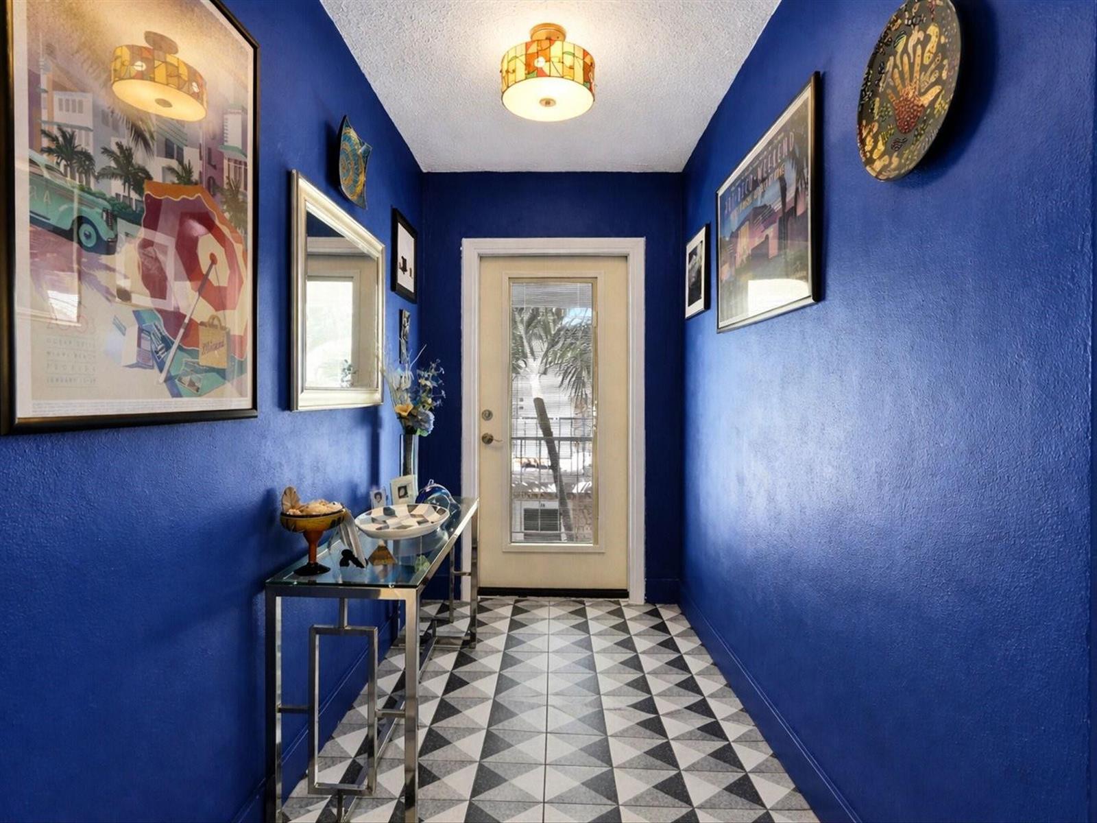 A hallway with vibrant blue walls, a geometric tiled floor, and a glass console table — 2501 W Golf Boulevard # 234, Pompano Beach FL 33064, POMPANO BEACH, FL