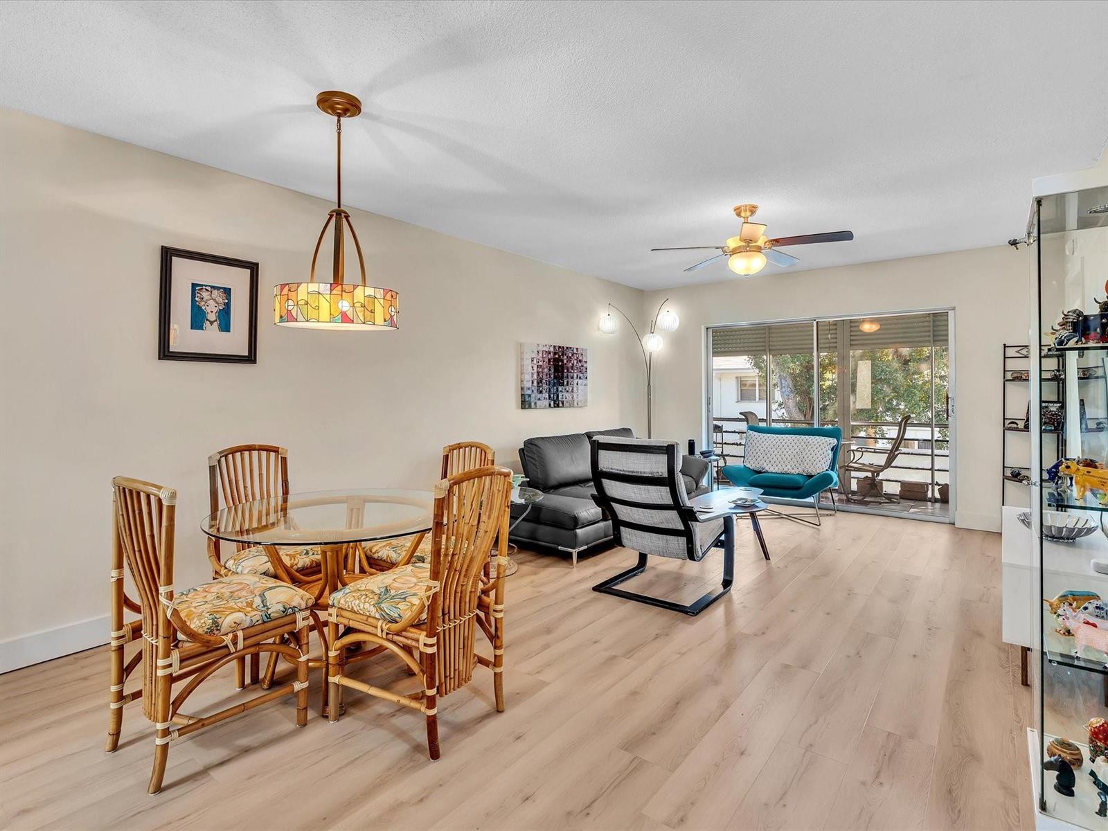 A living and dining area features light wood flooring, rattan chairs, and a glass sliding door — 2501 W Golf Boulevard # 234, Pompano Beach FL 33064, POMPANO BEACH, FL