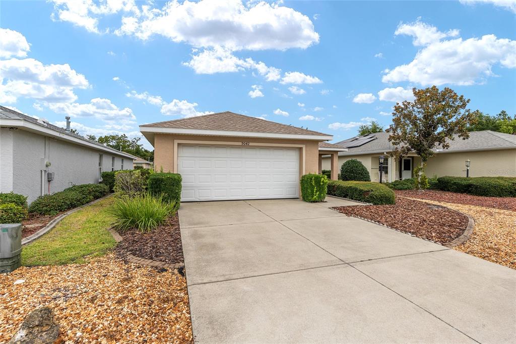 A single-story house with a two-car garage, a concrete driveway, and landscaped front yard — 9042 SW 102ND CIRCLE, OCALA, FL