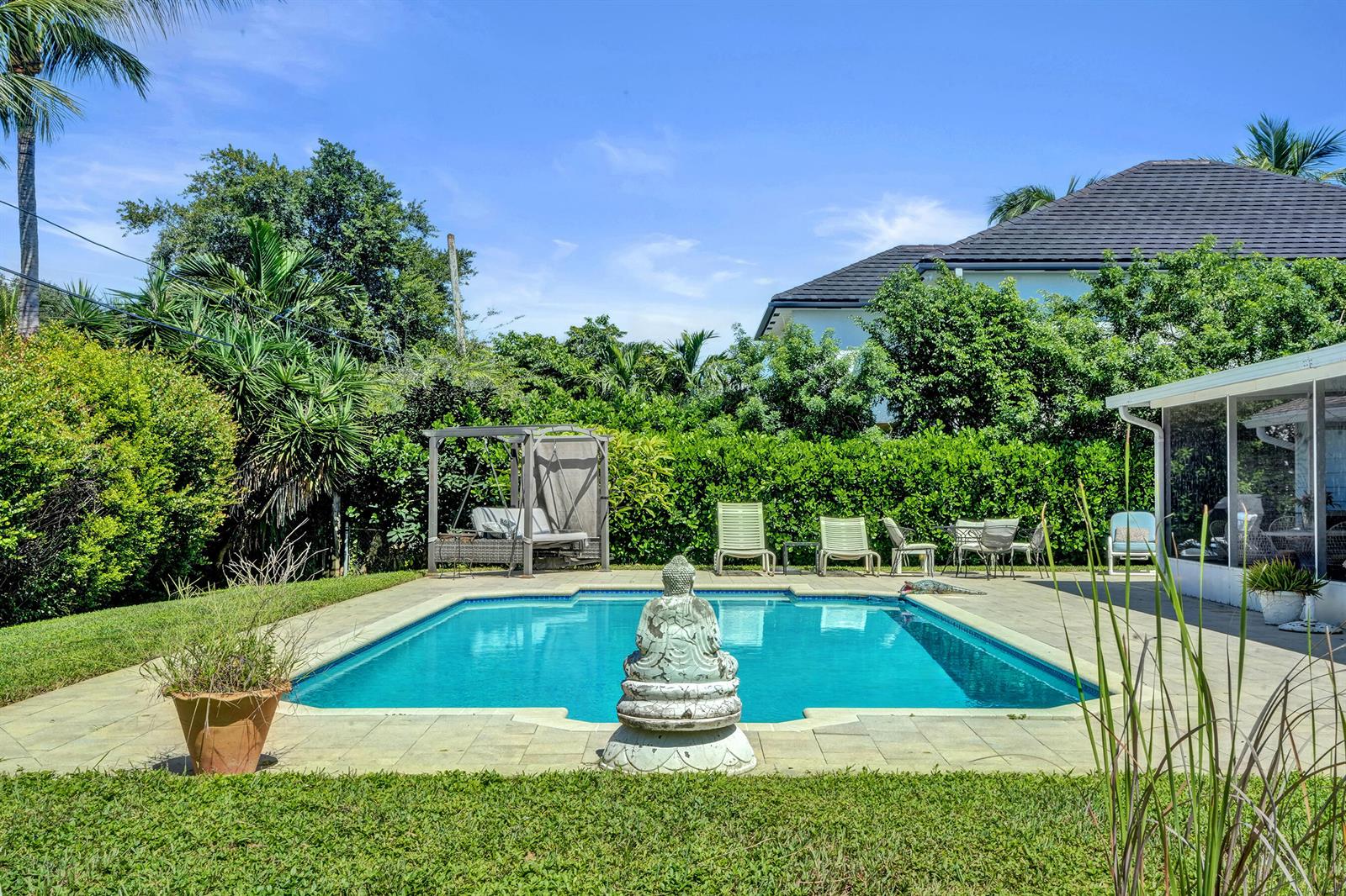A backyard swimming pool with a Buddha statue, lounge chairs, and a covered patio area — 710 NW 1st Avenue, Delray Beach FL 33444, DELRAY BEACH, FL