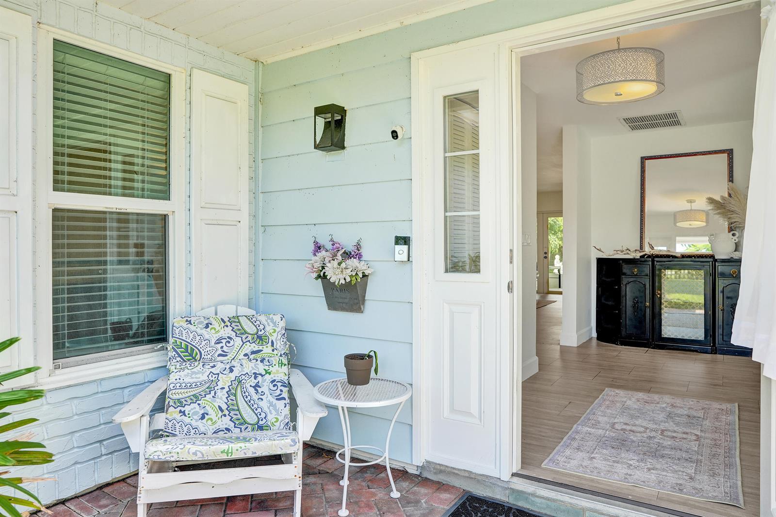 A light blue porch with a chair and table leads into a bright, tiled entryway — 710 NW 1st Avenue, Delray Beach FL 33444, DELRAY BEACH, FL