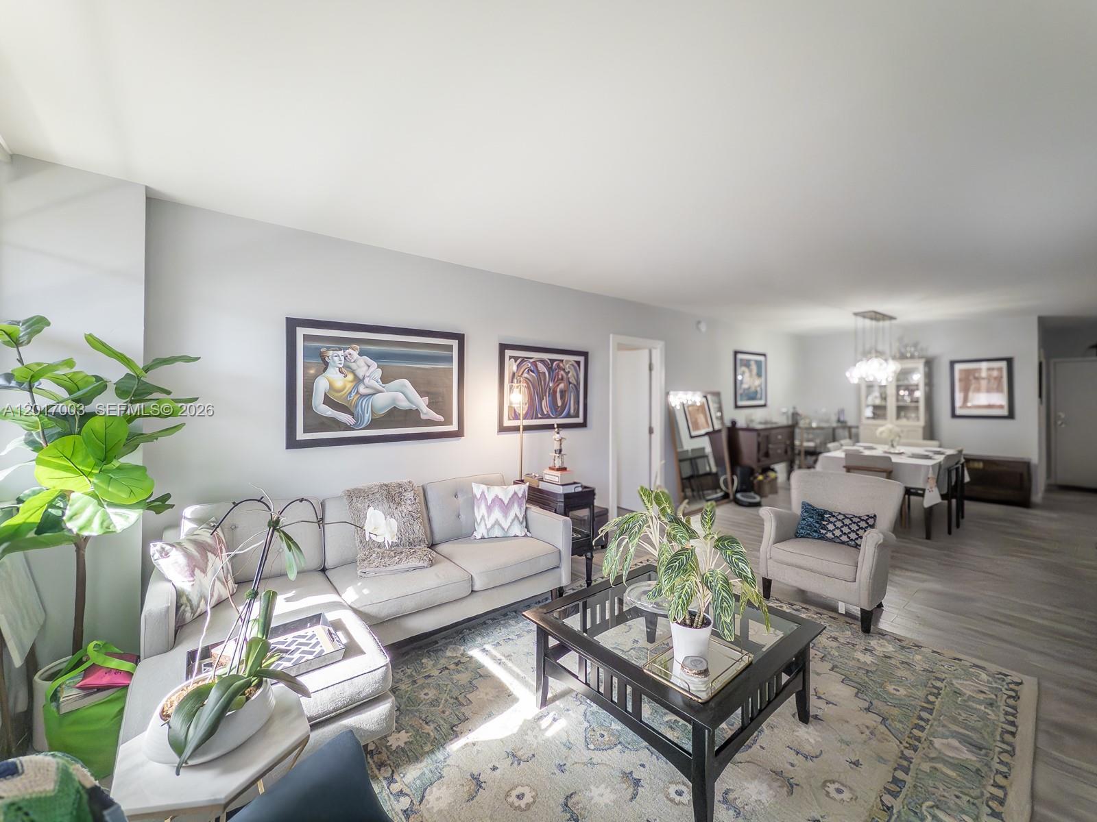 A living room features a grey sectional sofa, a glass-topped coffee table, and area rugs — 90 Edgewater Dr # 114, Coral Gables FL 33133, CORAL GABLES, FL