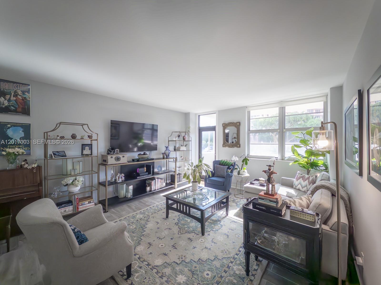 A living room features a television, glass coffee table, area rug, and neutral seating — 90 Edgewater Dr # 114, Coral Gables FL 33133, CORAL GABLES, FL