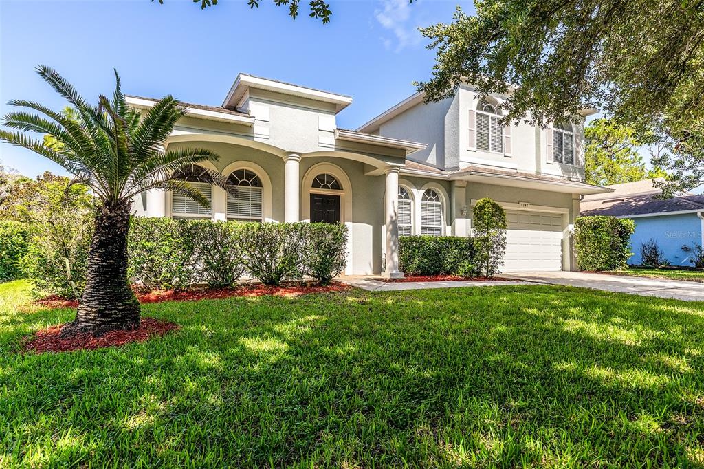 A two-story suburban house with a palm tree, arched windows, and a two-car garage — 4747 JETTY STREET, ORLANDO, FL