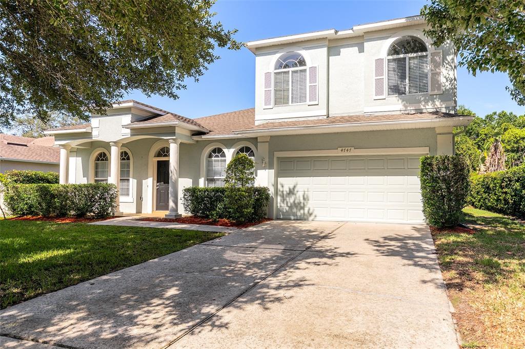 A two-story house with a light-colored exterior, a two-car garage, and a concrete driveway — 4747 JETTY STREET, ORLANDO, FL