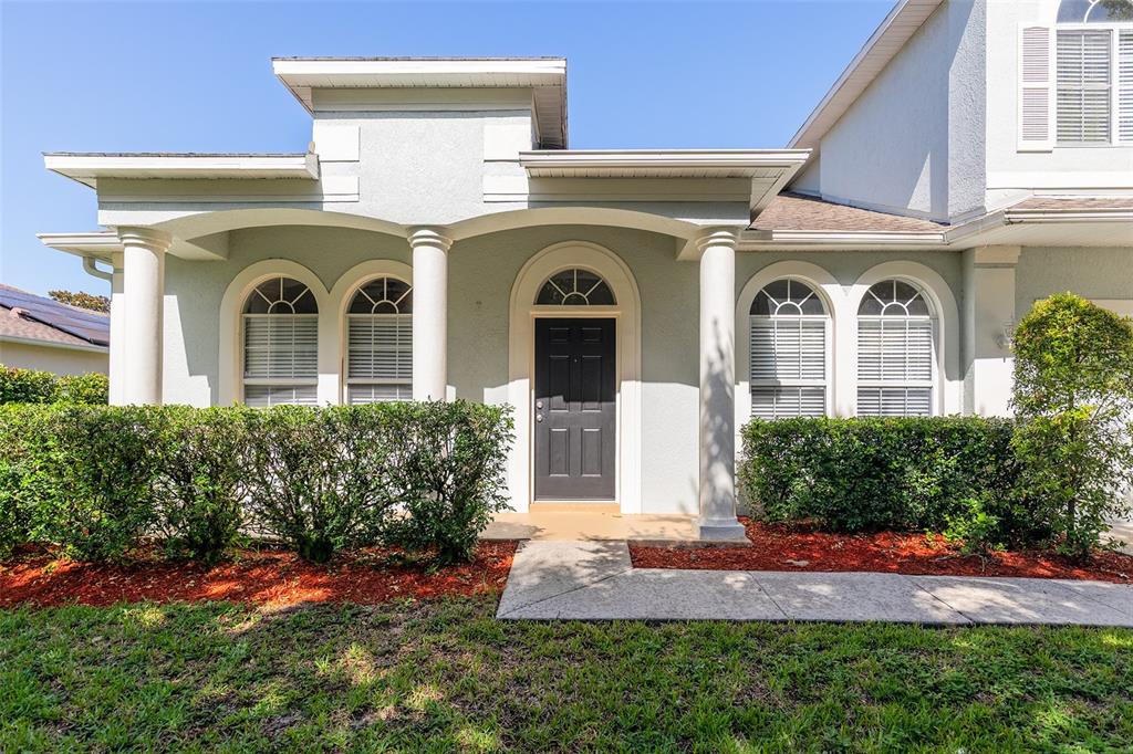 A light-colored house exterior features a covered entryway with columns and a dark front door — 4747 JETTY STREET, ORLANDO, FL