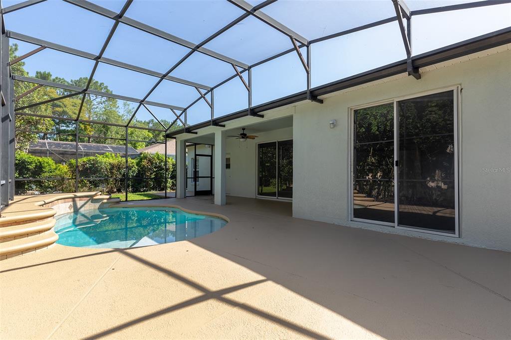 A covered patio features a swimming pool with tiered steps and sliding glass doors — 4747 JETTY STREET, ORLANDO, FL