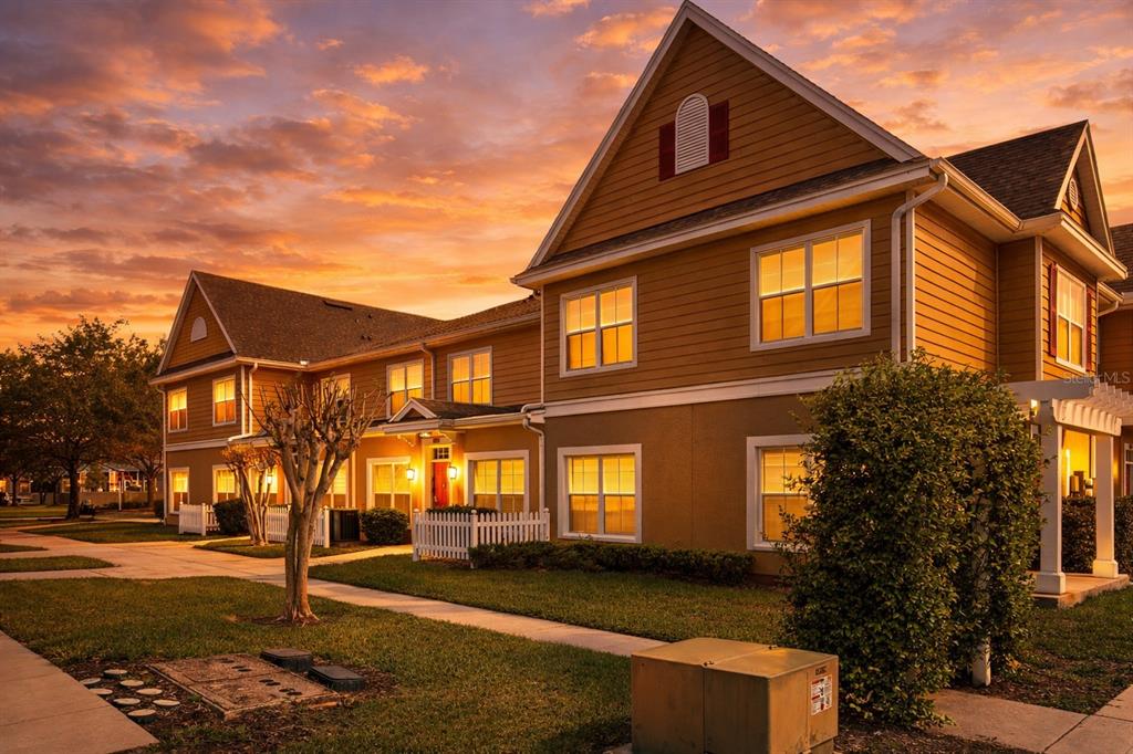 A two-story tan apartment building with a white picket fence at sunset — 4561 YELLOWGOLD ROAD E UNIT 103, KISSIMMEE, FL