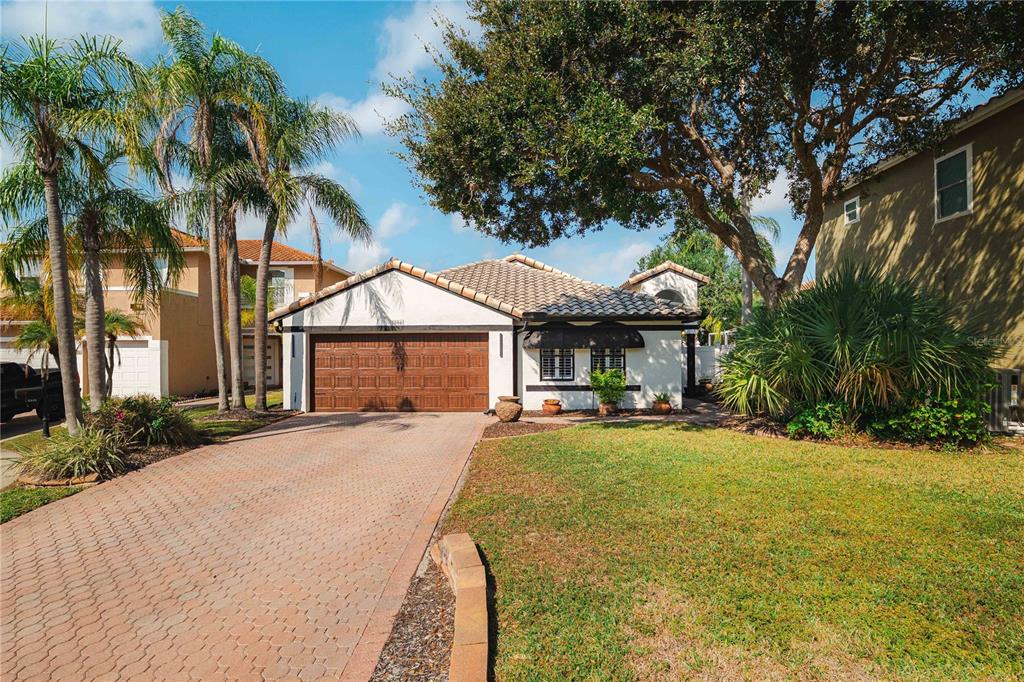 A single-story house with a tiled roof, a wooden garage door, and a paved driveway — 5806 CAY COVE COURT, TAMPA, FL
