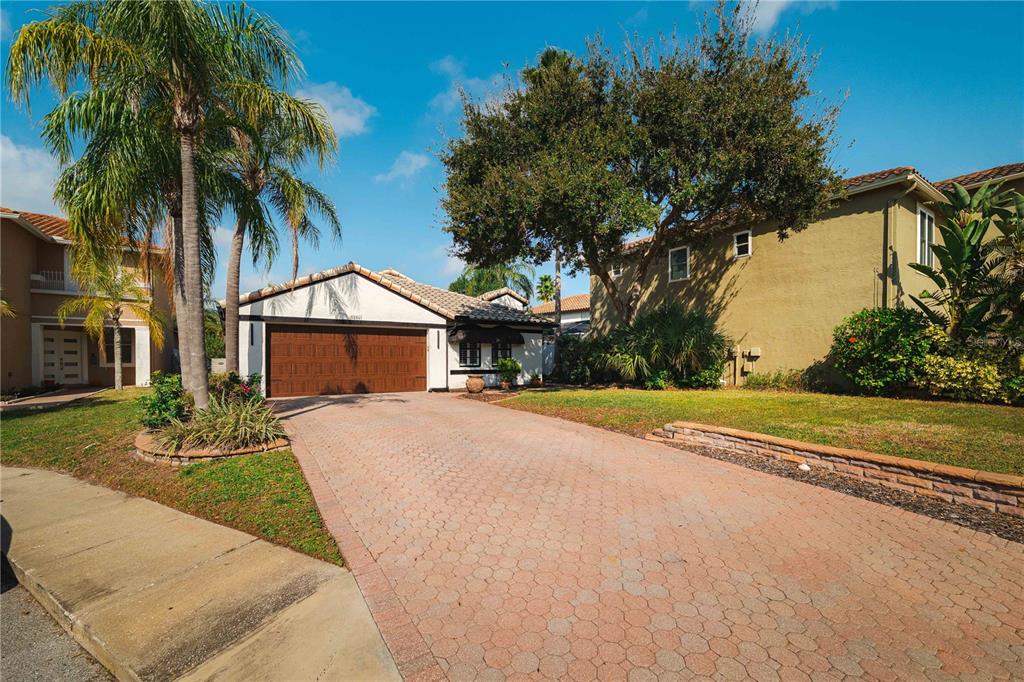 A single-story house with a brown garage door and a paved driveway under a blue sky — 5806 CAY COVE COURT, TAMPA, FL