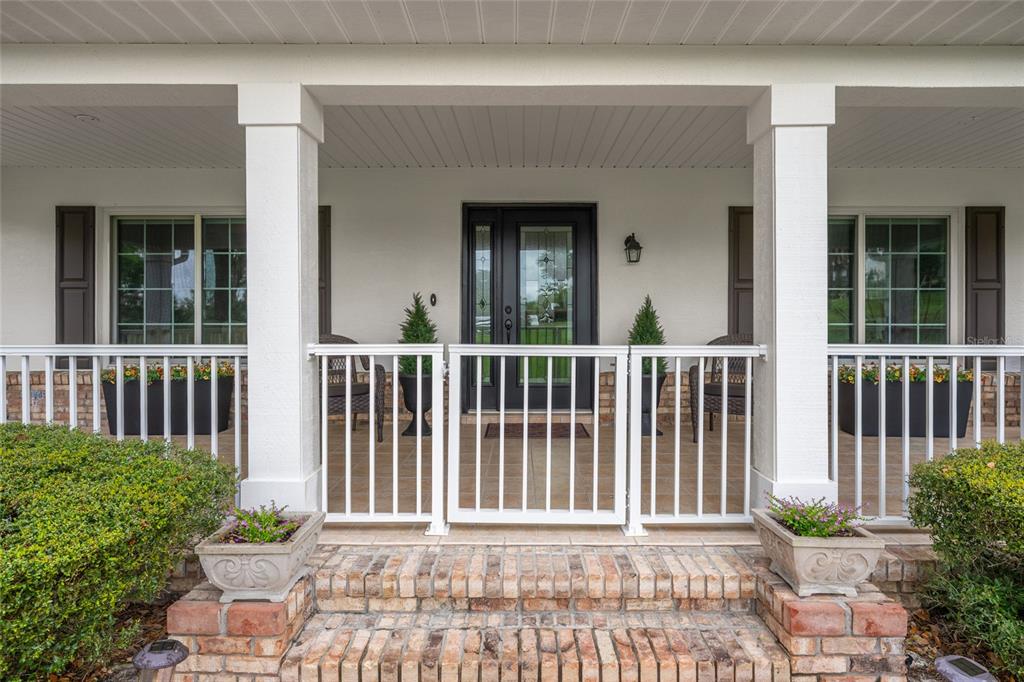 A covered front porch features a white railing, a central gate, and brick steps — 5402 NW 76TH COURT, OCALA, FL
