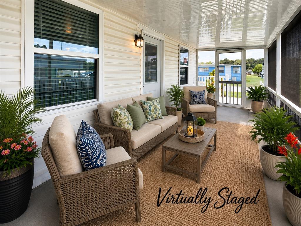 A covered porch features wicker furniture, potted plants, and a rug on a concrete floor — 39032 OLA AVENUE, ZEPHYRHILLS, FL