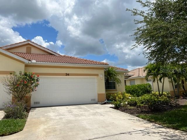 A tan house with a white garage door, a tiled roof, and a concrete driveway — 3181 MATECUMBE KEY ROAD UNIT 34, PUNTA GORDA, FL