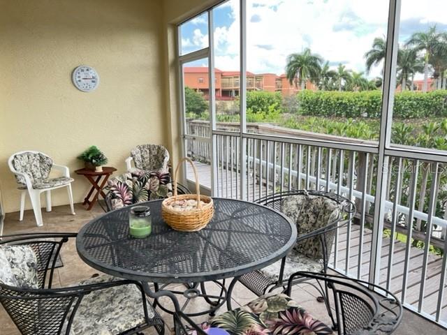 A screened-in patio features a round metal table, chairs, and a view of palm trees — 3181 MATECUMBE KEY ROAD UNIT 34, PUNTA GORDA, FL