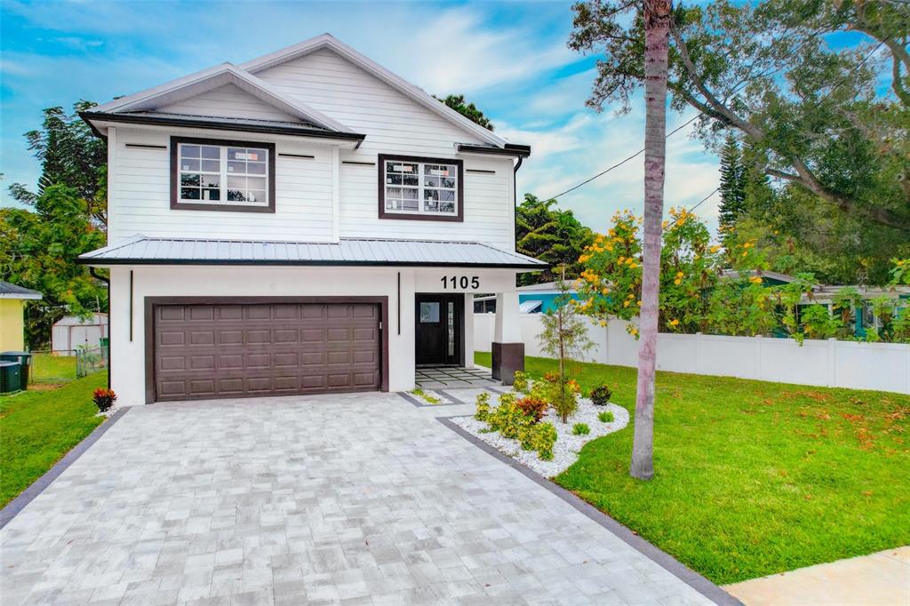 A two-story white house with a paved driveway, a garage, and a landscaped front yard — 1105 CONANT AVENUE, SAFETY HARBOR, FL