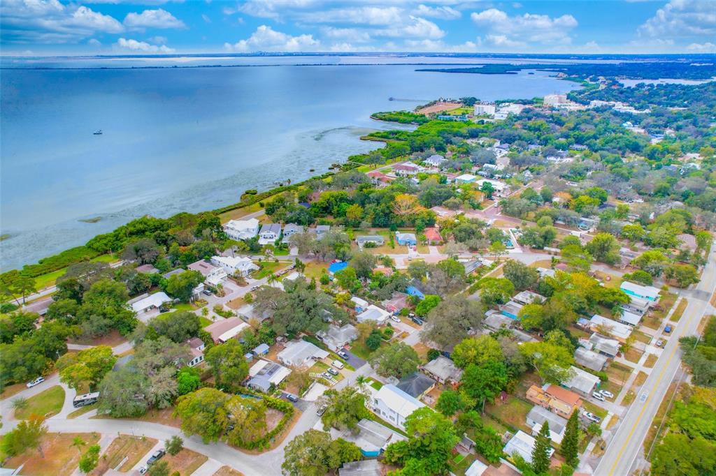 An aerial view shows a coastal neighborhood with houses nestled among trees near the water — 1105 CONANT AVENUE, SAFETY HARBOR, FL