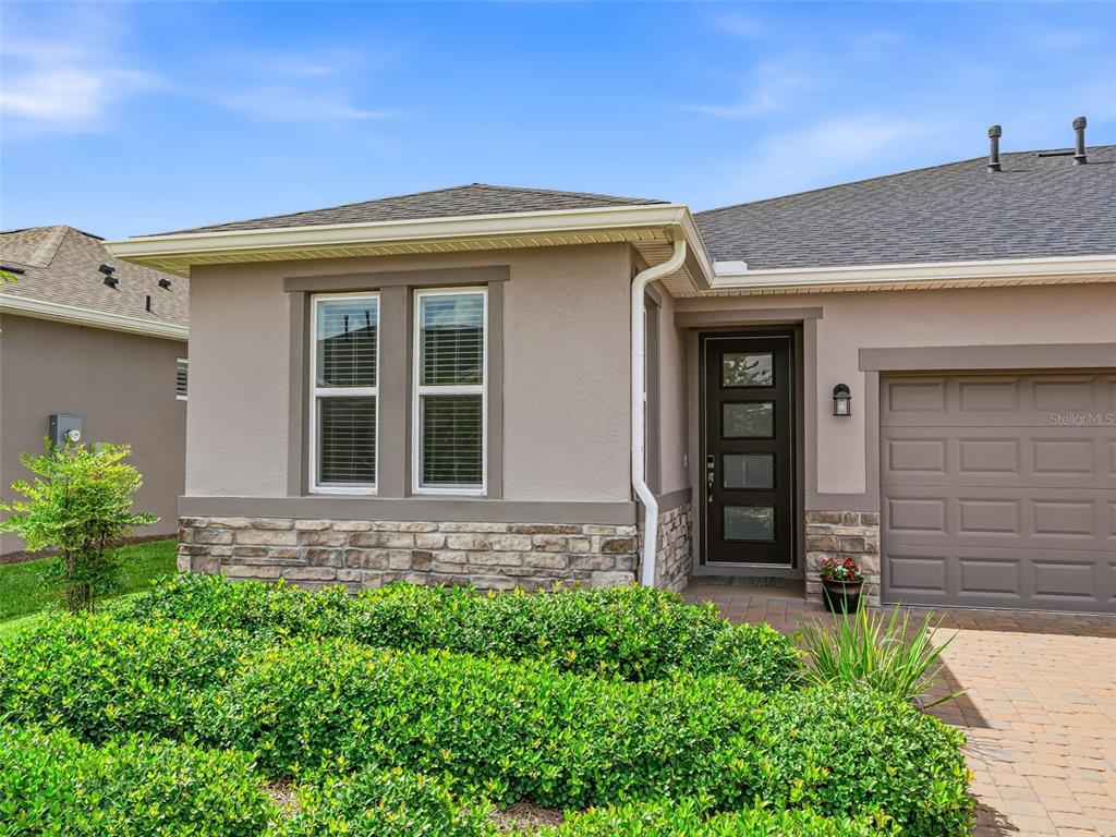 The exterior of a house features a stone base, tan stucco walls, and a front door — 5329 NW 34TH STREET, OCALA, FL