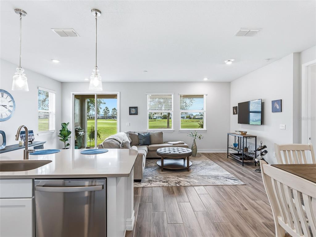 An open-concept living room and kitchen area with light wood-look tile flooring and sliding doors — 5329 NW 34TH STREET, OCALA, FL