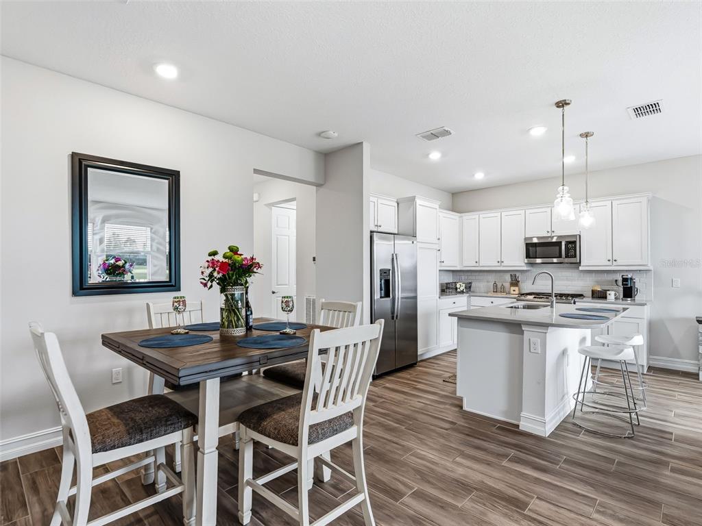 A dining area with a wooden table and white chairs sits beside a modern kitchen — 5329 NW 34TH STREET, OCALA, FL