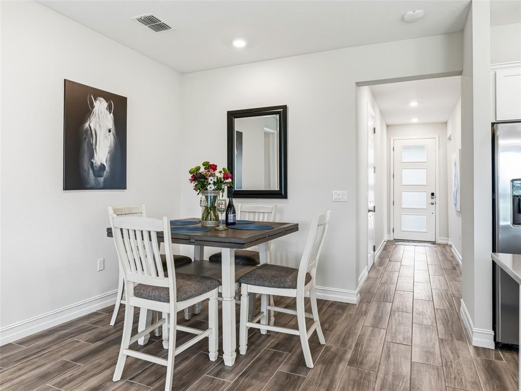 A dining area features a square wooden table with four white chairs and wood-look flooring — 5329 NW 34TH STREET, OCALA, FL